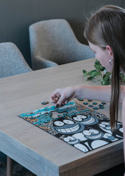 Person working on Penguins MasterPiece 3mm wooden puzzle.
