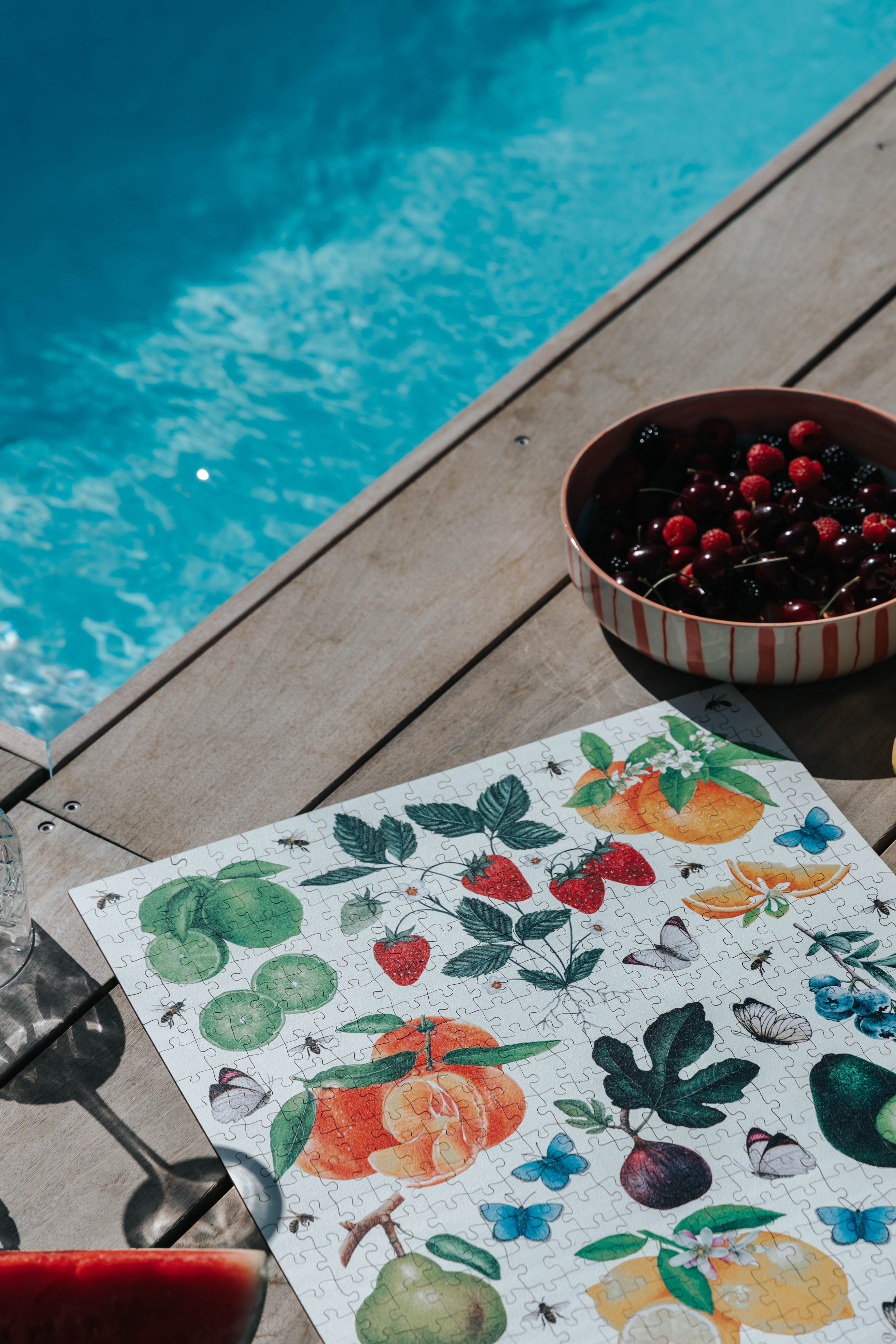 Fruit-themed placemat on a wooden deck by a pool