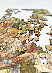 Fynbos Symphony is a MasterPiece wooden jigsaw puzzle that features a stunning nature-inspired illustration that is rich with diverse flora and fauna. Soft, earthy tones create a vintage botanical aesthetic, while vibrant birds and delicate insects bring the scene to life. Precision-cut from 3mm thick wood and expertly printed, our MasterPiece puzzles offer a tactile and satisfying puzzling experience like no other. They are perfect for art lovers, bird lovers and anyone looking for a thoughtful gift.