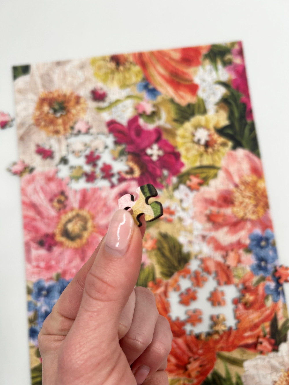 Hand holding a puzzle piece over a floral-patterned book