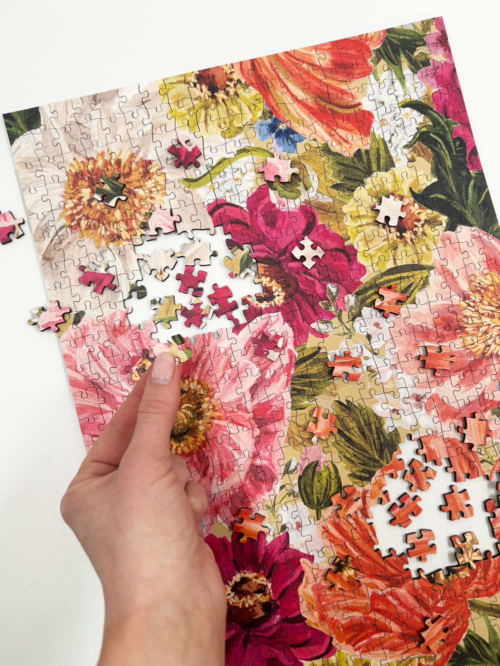 Floral puzzle with a hand placing a piece on a white background