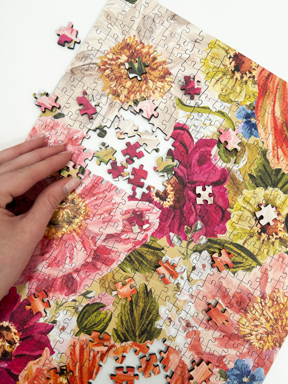 Floral puzzle with a hand placing a piece, featuring vibrant flowers and leaves.