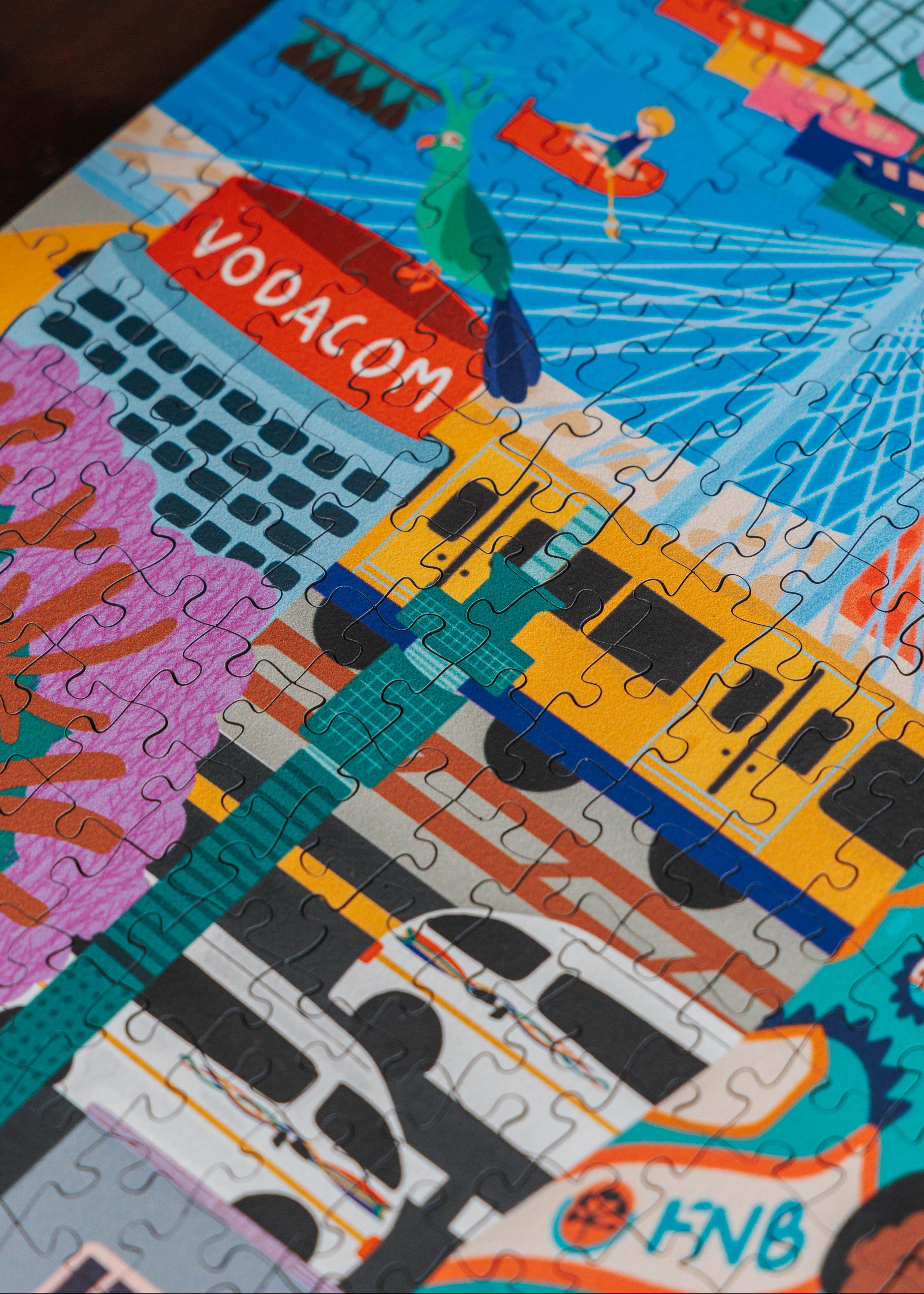 Colorful puzzle with Vodacom and FNB branding, held by a hand. Johannesburg by Kelly McChesney Puzzle