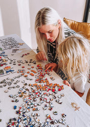Two people working on a puzzle together at a table.