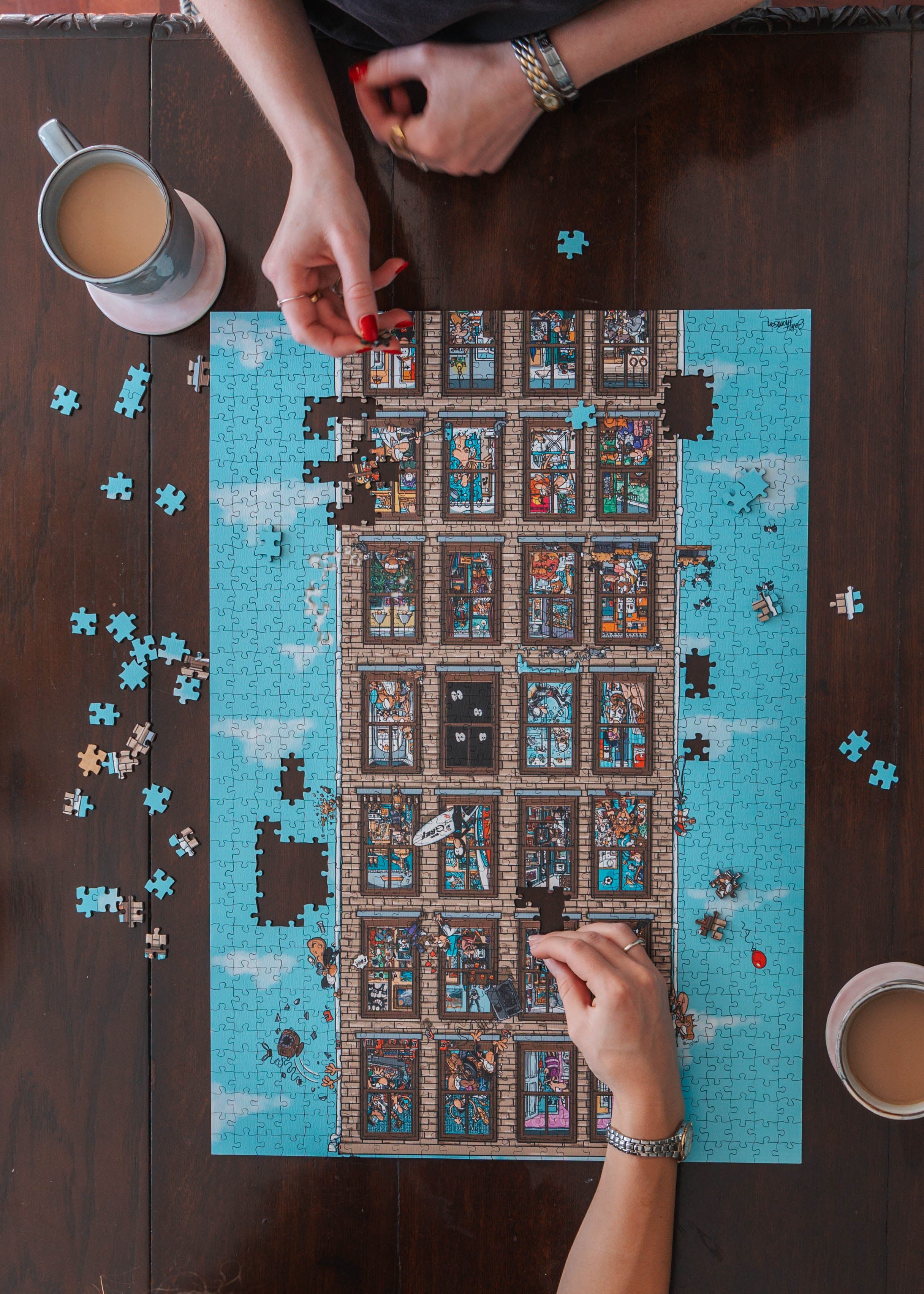 Two people working on a wooden puzzle on a wooden table with coffee cups.