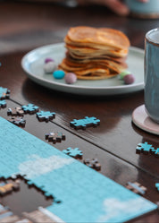Pancakes with syrup, colorful candies, and a wooden puzzle on a wooden table.