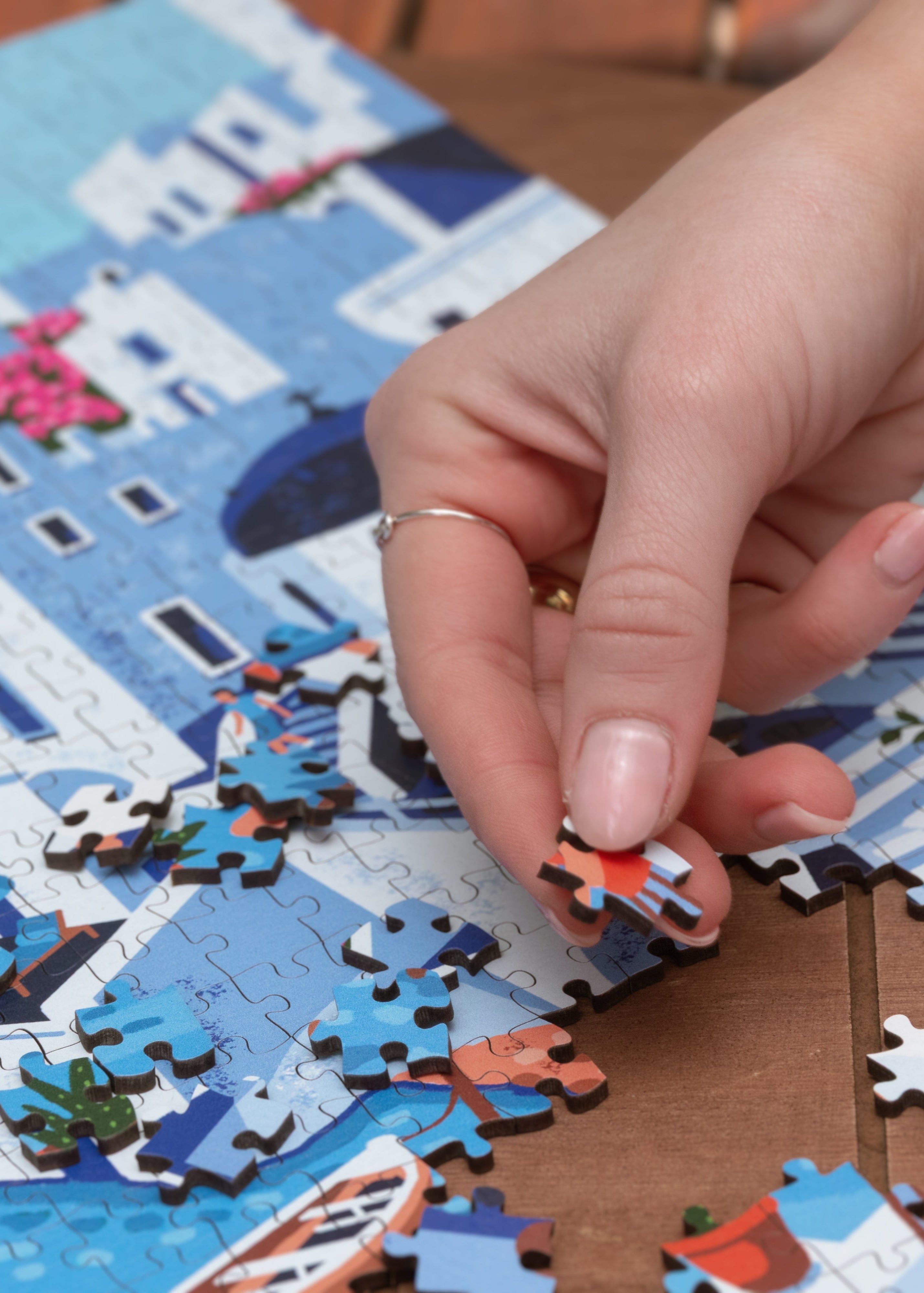Hand placing a puzzle piece on a Santorini-themed puzzle