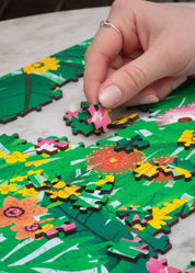 Hand placing a puzzle piece on a floral-themed puzzle