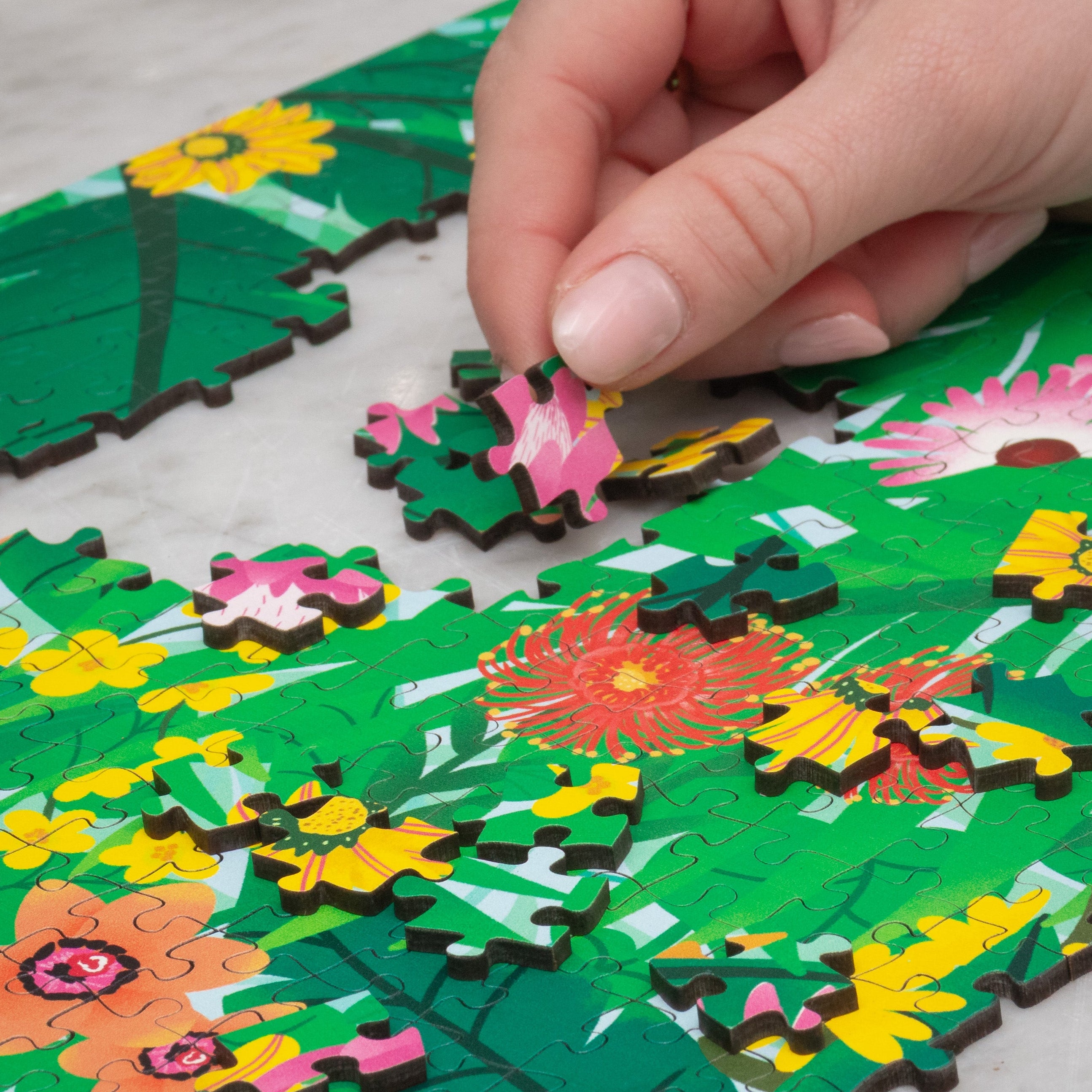 Hand placing a puzzle piece on a floral-themed puzzle