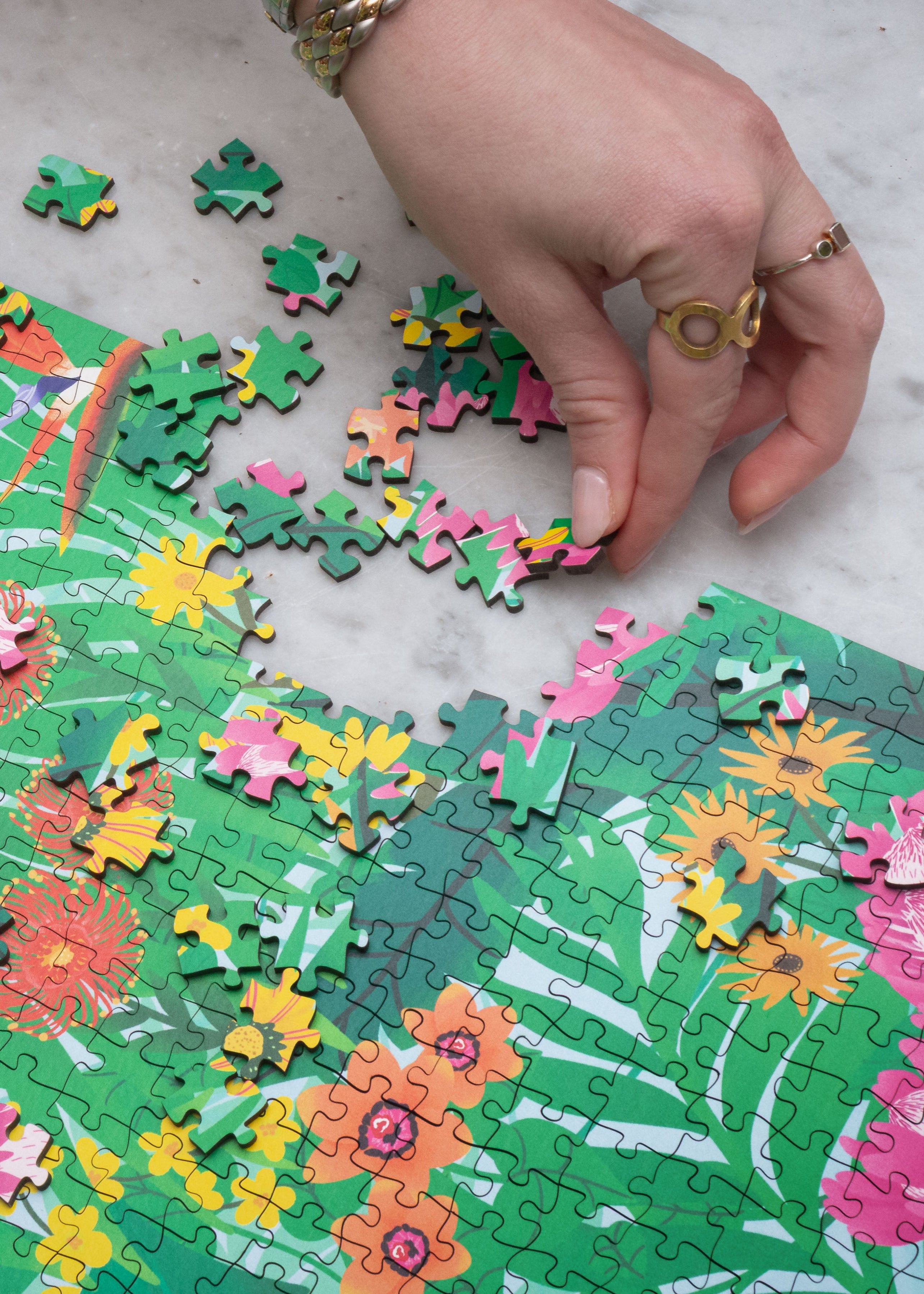 Hand placing puzzle pieces on a floral-themed puzzle