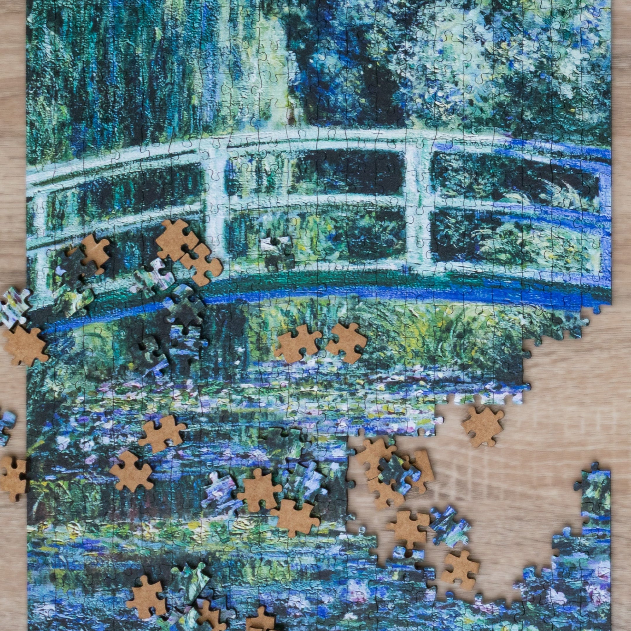 Jigsaw puzzle with completed pieces on a Monet-style painting of a bridge over water.