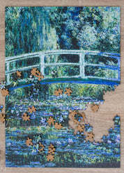 Jigsaw puzzle with completed pieces on a Monet-style painting of a bridge over water.