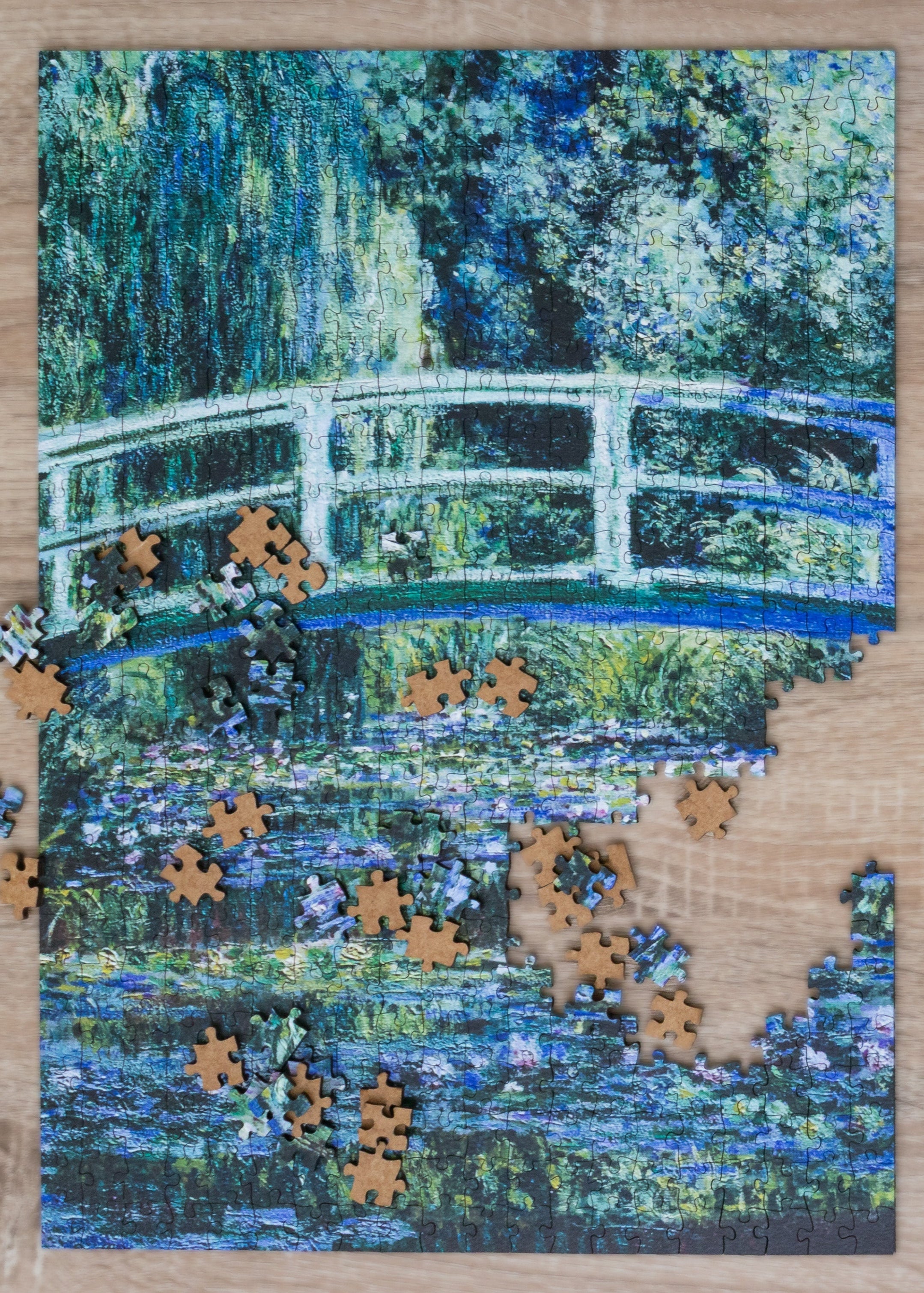 Jigsaw puzzle with completed pieces on a Monet-style painting of a bridge over water.