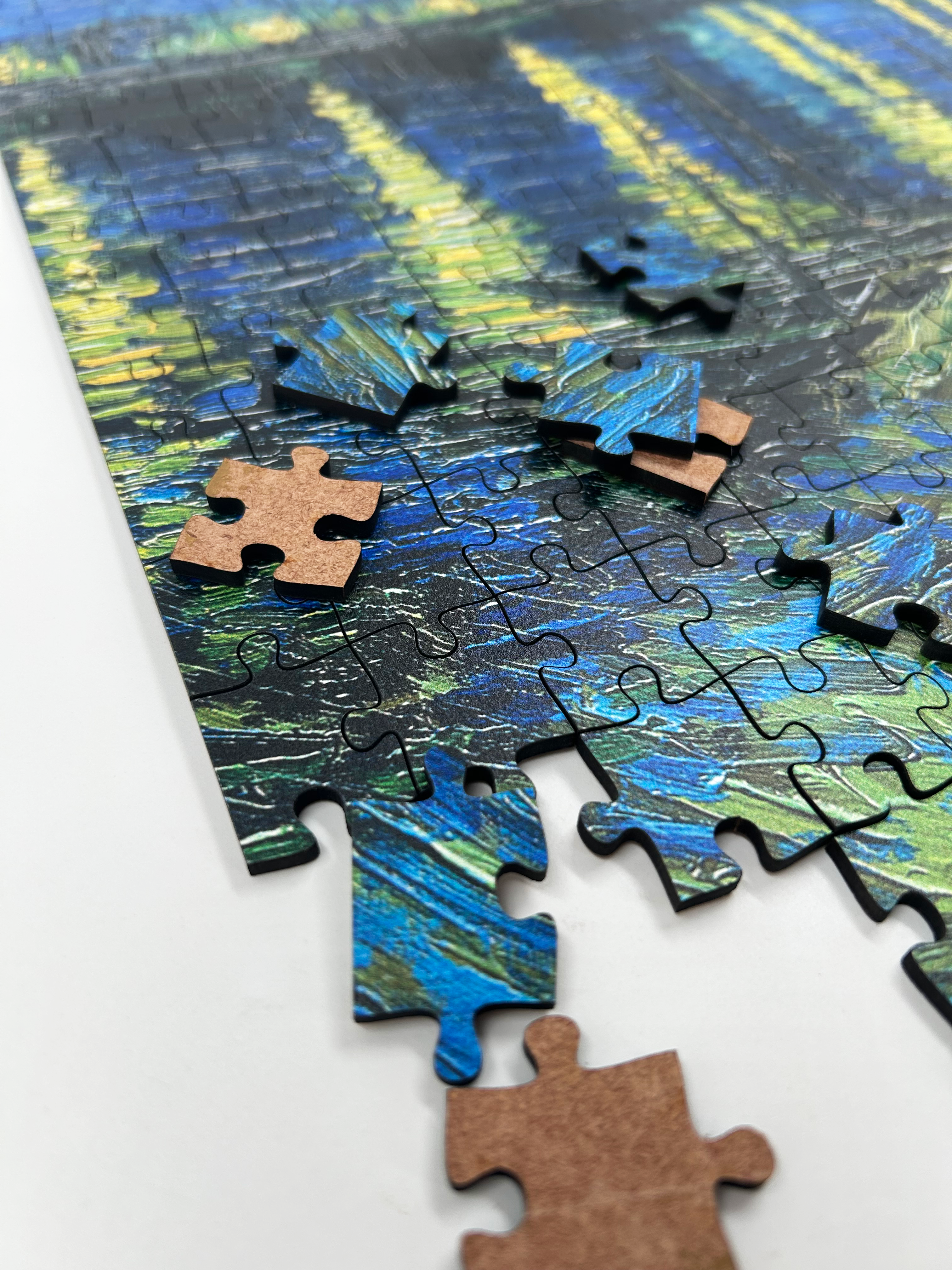 Starry Night Over the Rhône is a MasterPiece wooden jigsaw puzzle of Vincent Van Gogh's painting that depicts a serene nighttime scene of a deep blue sky filled with shimmering stars, their light reflecting off the Rhône River. Precision-cut from 3mm thick wood and expertly printed, our MasterPiece puzzles offer a tactile and satisfying puzzling experience like no other. They are perfect for classic art lovers, floral enthusiasts and anyone looking for a thoughtful gift.