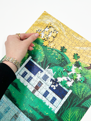 A wooden jigsaw puzzle featuring an illustration of the Zevenwacht Wine Estate manor house. Perfect for art lovers and anyone looking for a thoughtful gift. 